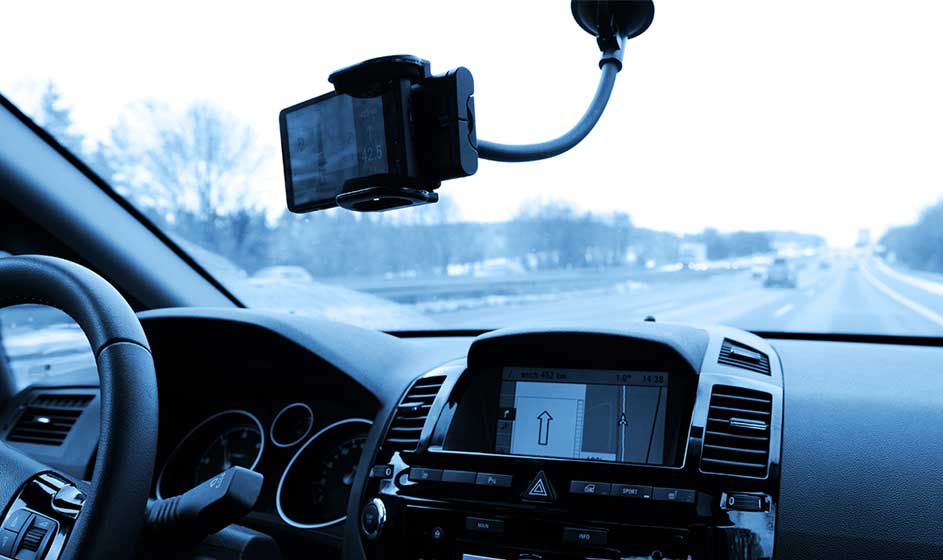 Un conducteur roule sur une route enneigée tandis qu’une caméra fixée au pare-brise filme le trajet; l’écran de navigation affiche l’itinéraire à suivre.