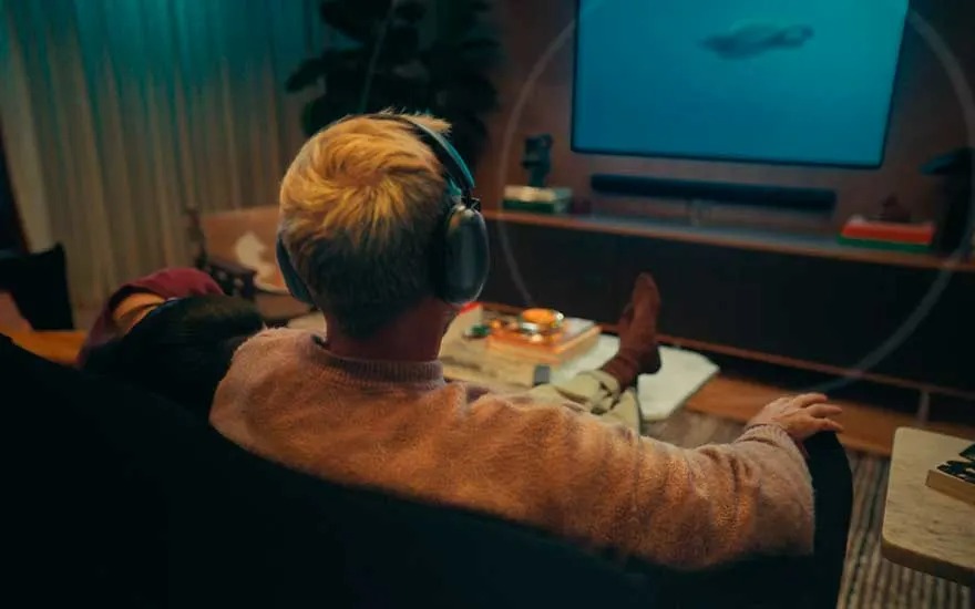 Salon sombre avec canapé, table basse, téléviseur et casque audio.