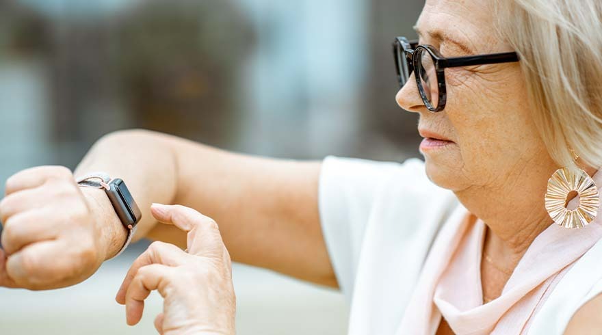 Een close-up van een horloge om een pols, met een vinger die het scherm aanraakt, tegen een vage achtergrond.