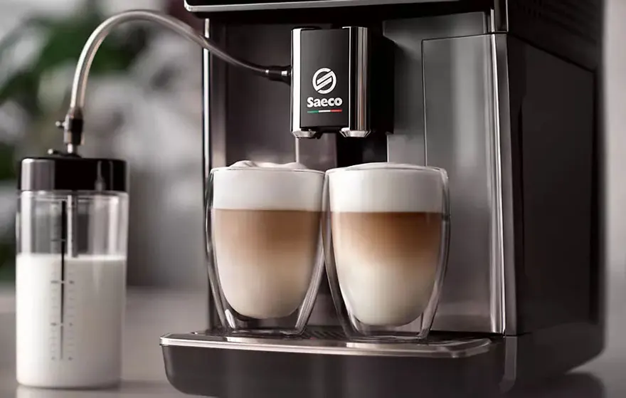 Twee latte macchiato's in glazen, gemaakt door een Saeco koffiemachine met melkreservoir.