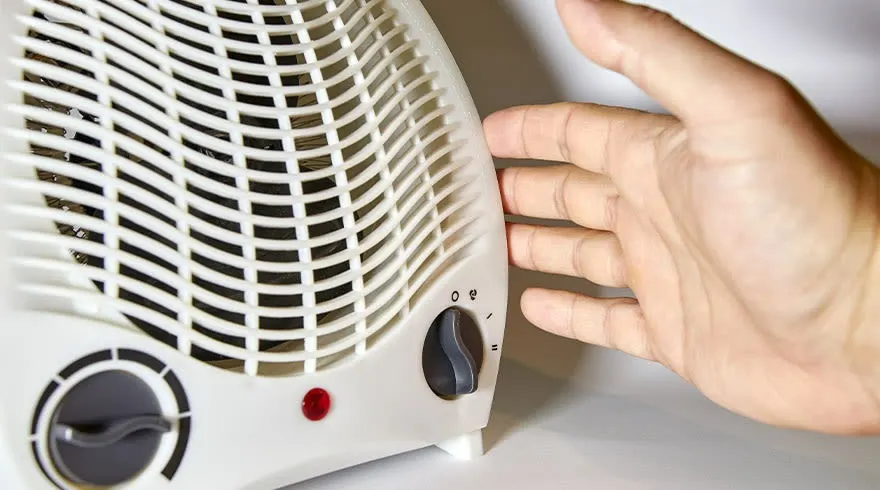 Radiateur blanc avec grille, boutons noirs et témoin rouge. Une main est sur le côté.