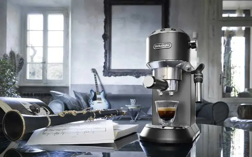 Machine à espresso compacte prépare un café sur plan brillant, entourée de partitions, clarinette et guitare dans salon cosy.