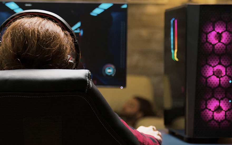 Un joueur avec un casque assis dans un fauteuil gaming noir devant un PC avec 