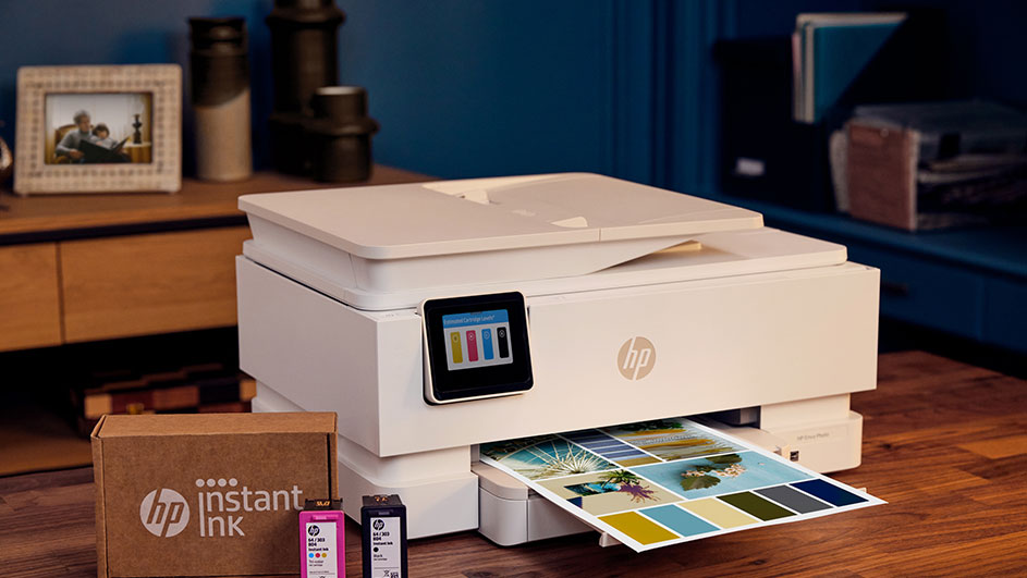 Imprimante HP imprimant une page couleur à côté d’un emballage HP Instant Ink et de cartouches.