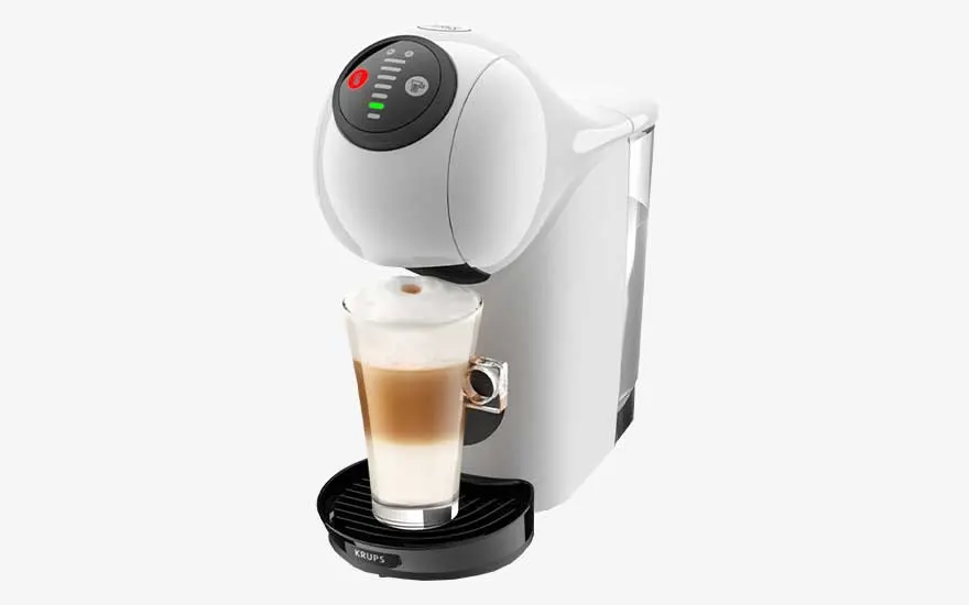 A white Krups coffee machine pours a creamy latte into a tall glass, with round controls and a transparent water reservoir.