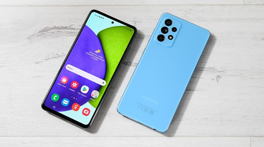 Deux smartphones sont posés sur une surface blanche en bois. Un téléphone a un écran allumé, l'autre est bleu.