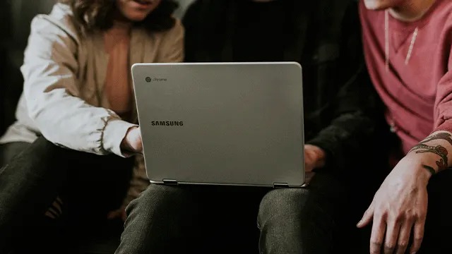 Een grijze Samsung laptop staat op schoot. De achtergrond is wazig.