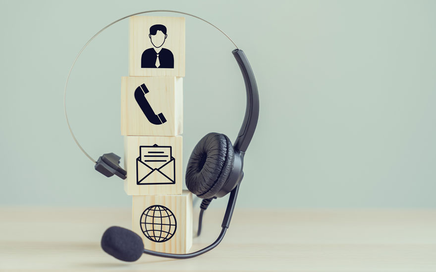 Een zwarte headset staat naast een stapel houten blokken met icoontjes op een lichte achtergrond.