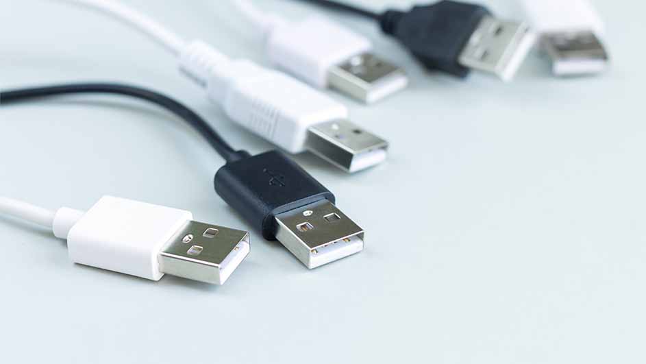 Gros plan de câbles USB blancs et noirs sur fond clair. Les connecteurs sont en métal argenté.