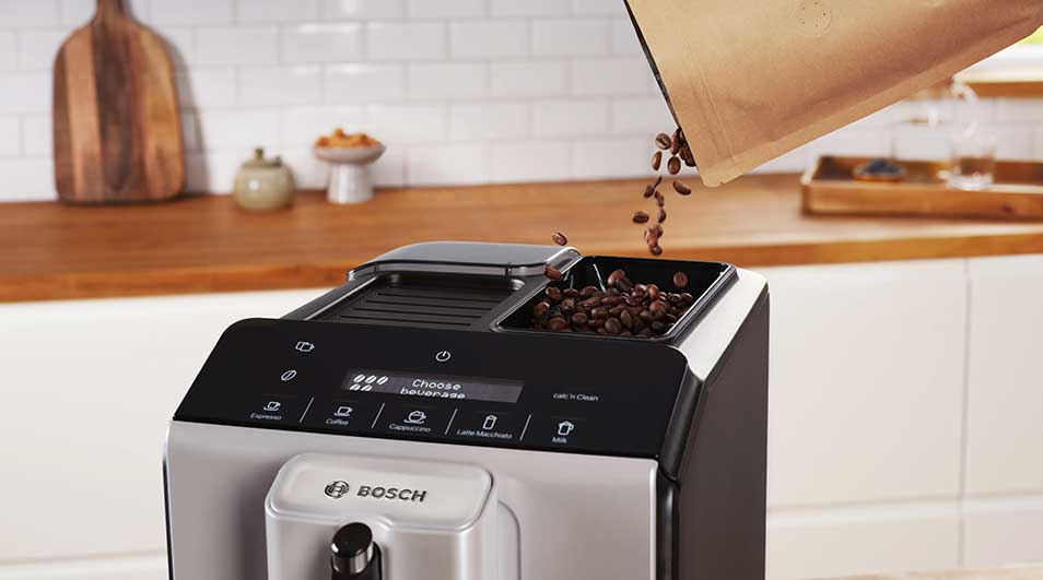 Machine Bosch à grains tandis que des grains brillants tombent dans le réservoir, prêts pour un café fraîchement moulu en cuisine.