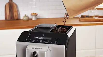 Machine Bosch à grains tandis que des grains brillants tombent dans le réservoir, prêts pour un café fraîchement moulu en cuisine.
