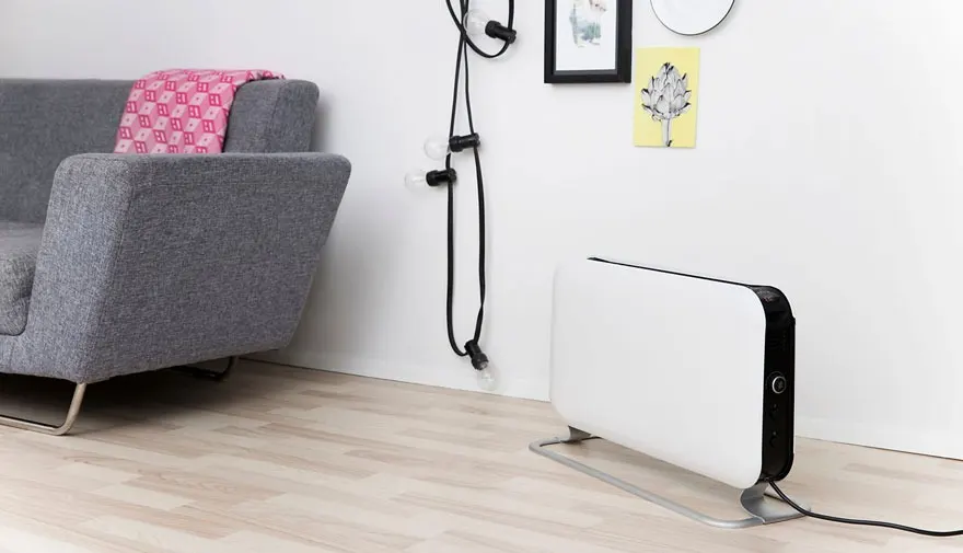 Un salon présente un canapé gris, un radiateur blanc sur un plancher en bois, et une décoration murale minimaliste.