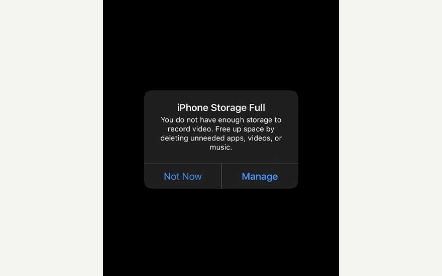 Black iPhone screen showing “iPhone Storage Full” alert, warning there’s no space left and offering options to manage storage.