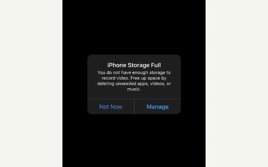 Black iPhone screen showing “iPhone Storage Full” alert, warning there’s no space left and offering options to manage storage.