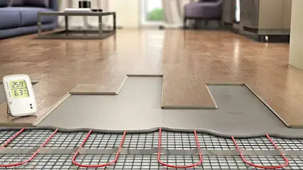 Installation de chauffage au sol. Tapis chauffant rouge sous des planches de bois. Un thermostat indique 25.9 degrés.