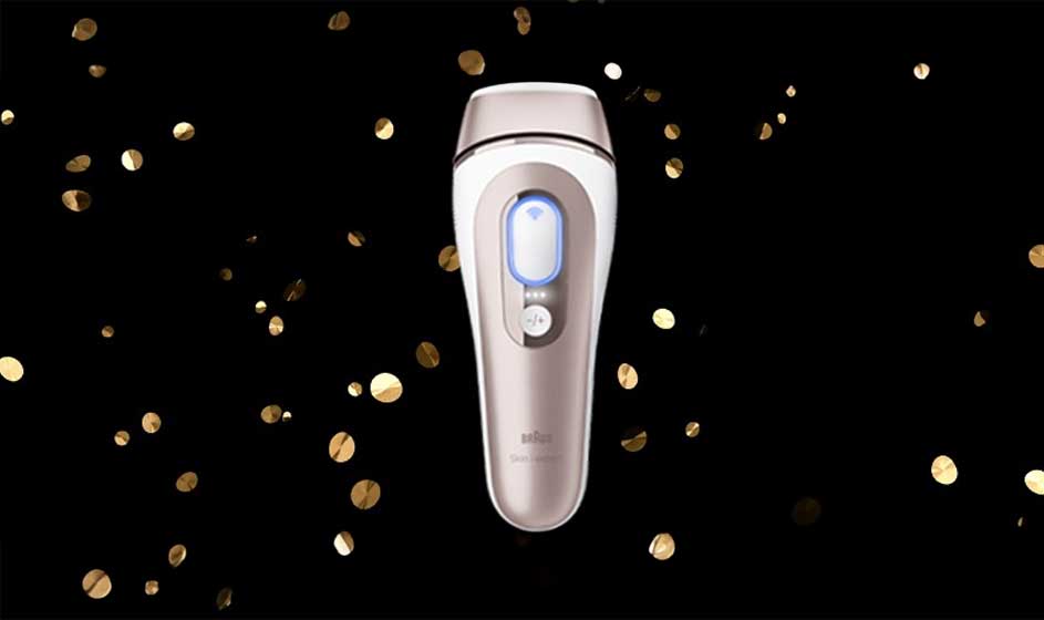 Op de afbeelding staat een Braun ontharingsapparaat met goudkleurige accenten, omringd door gouden confetti op een zwarte achtergrond.