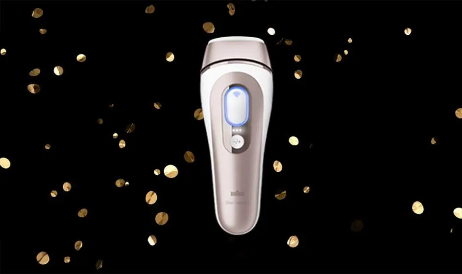 Op de afbeelding staat een Braun ontharingsapparaat met goudkleurige accenten, omringd door gouden confetti op een zwarte achtergrond.