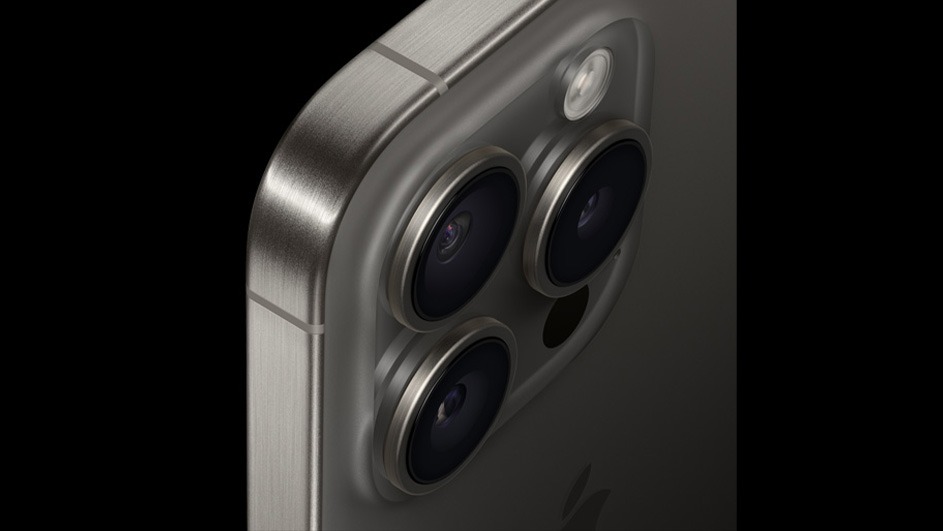 Gros plan d'un téléphone gris avec trois objectifs de caméra circulaires et un flash sur un fond noir.