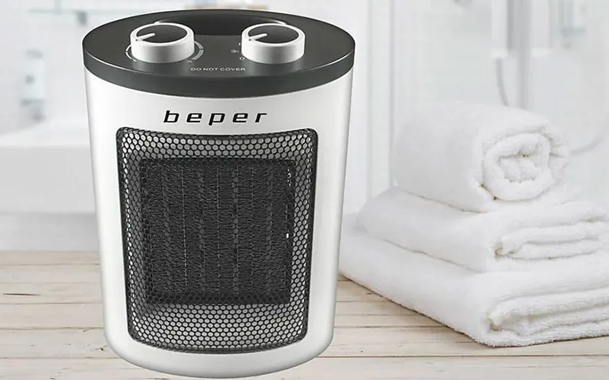 Un radiateur blanc "beper" avec une grille noire, posé près d'une pile de serviettes blanches.
