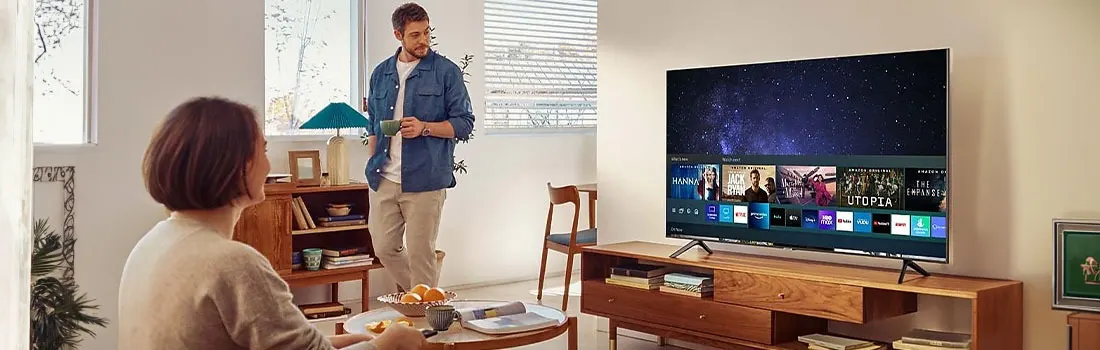 A living room scene features a TV displaying streaming options, a wooden cabinet, and a table with fruit and magazines.