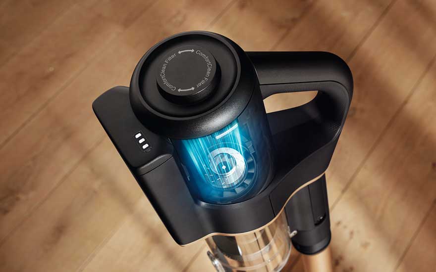 Een zwarte steelstofzuiger staat op een houten vloer, met een blauw verlichte stofcontainer en batterij-indicator.