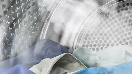 Intérieur d'un tambour de machine à laver avec du linge bleu, blanc et gris clair. Le tambour est en métal perforé.