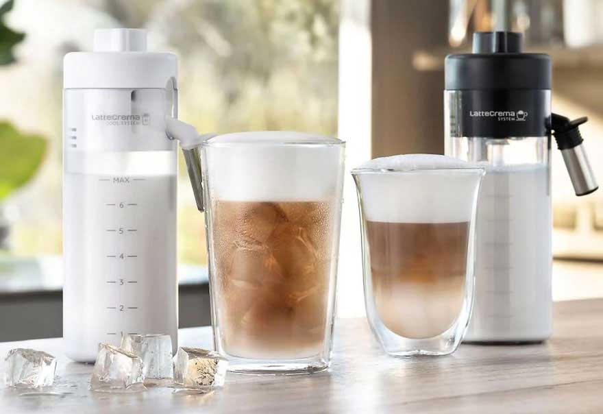 Twee glazen koffie met melk en ijs staan naast twee melkopschuimers op een houten tafel.