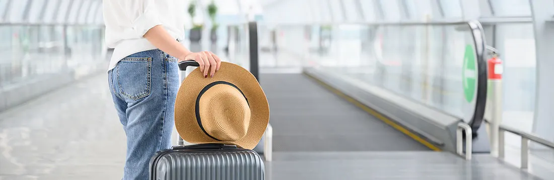 Hall d'aéroport lumineuse avec tapis roulant. Valise noire avec chapeau beige à bord noir.