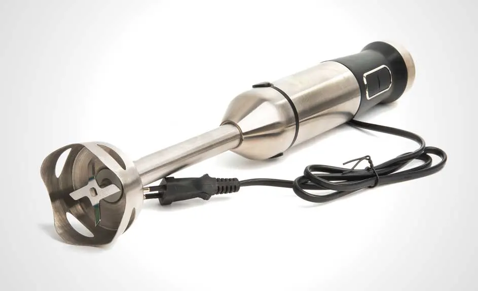 Un mixeur plongeant en métal argenté avec un manche noir et un cordon d'alimentation noir sur un fond blanc.