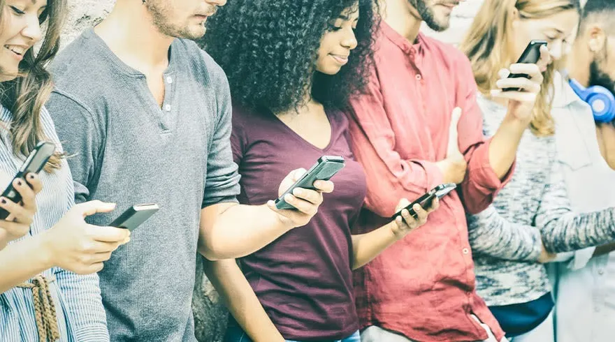 Een rij mensen, elk met een smartphone in de hand, tegen een achtergrond van een gestreepte muur.