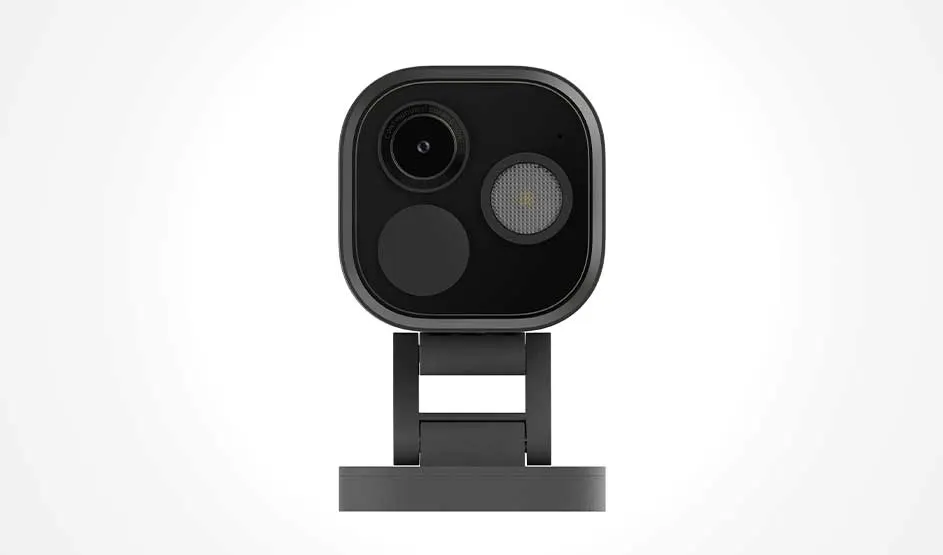 Een compacte zwarte slimme camera staat frontaal op een standaard, met lens en sensor zichtbaar tegen een lichte achtergrond.