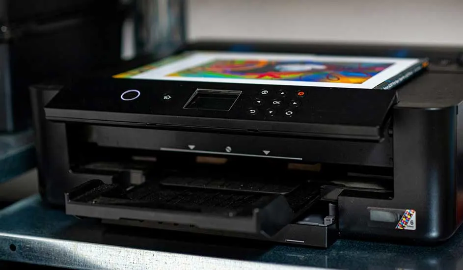 Een zwarte printer staat op een tafel. Er ligt een afdruk met kleurenfoto's bovenop de printer.