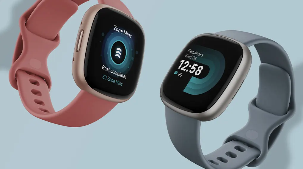 Twee smartwatches met touchscreen. Eén met een roze band en de andere met een grijze band, op een blauwe achtergrond.