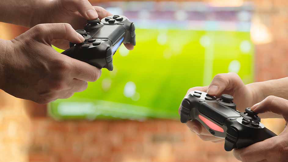 Deux mains tiennent des manettes de jeu noires devant un écran vert.