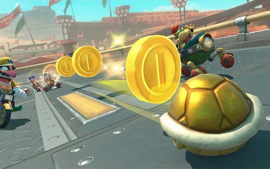 Op een grijze baan liggen gouden munten en een schild. Op de achtergrond zijn andere voertuigen en een zanderige omgeving te zien.