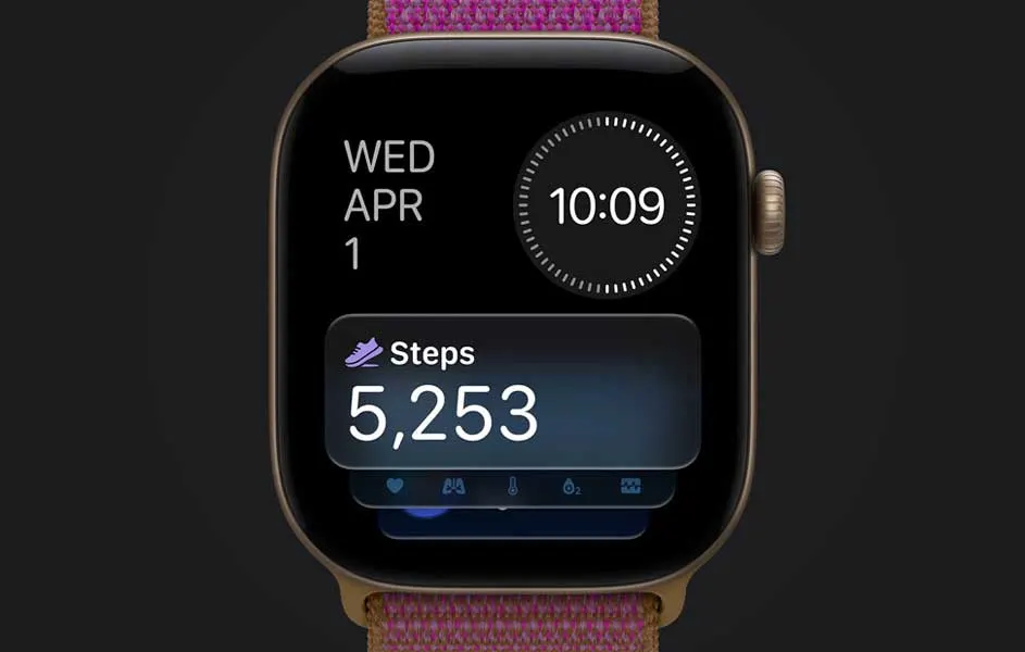 Een smartwatch met een roze gevlochten band staat tegen een donkere achtergrond. Het scherm toont woensdag 1 april, de tijd 10:09 en 5.253 stappen.