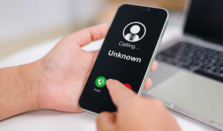 Une main tient un smartphone affichant un appel entrant d’un numéro inconnu, tandis qu’un doigt s’apprête à appuyer sur le bouton vert.