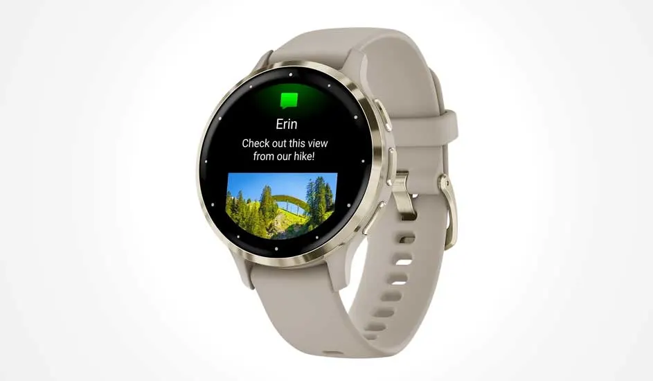 Une montre connectée beige à écran rond affiche un message avec texte et photo d’un pont dans un paysage vert et boisé sur l’écran.