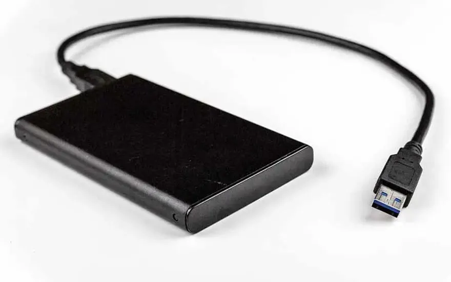 Een zwarte externe harde schijf met een USB 3.0-kabel ligt op een witte achtergrond, klaar voor aansluiting op een apparaat.