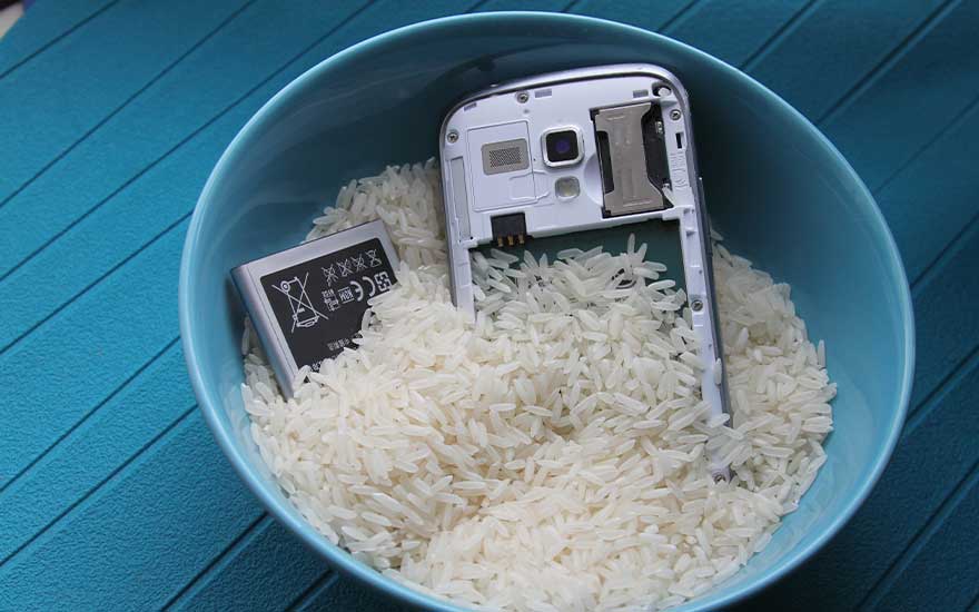 Des composants d’un téléphone sont placés dans un bol de riz, une astuce maison pour absorber l’humidité après un dégât d’eau.