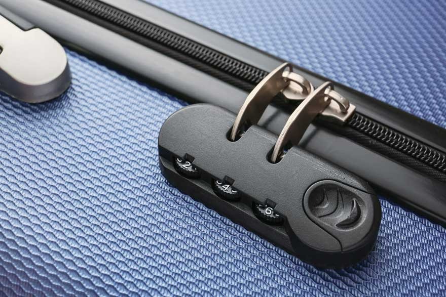 Een blauwe koffer met een zwart cijferslot en een rits. Het slot is bevestigd aan de rits.