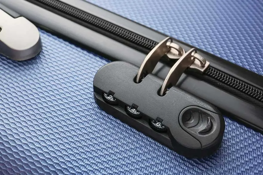 Een blauwe koffer met een zwart cijferslot en een rits. Het slot is bevestigd aan de rits.