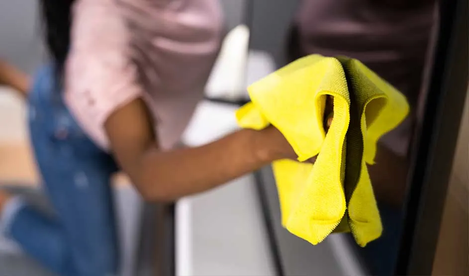 Someone wipes a smooth surface with a yellow cloth, with focus on the hand and the motion.