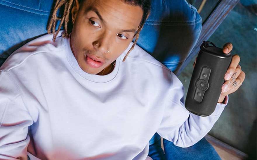 Un homme tient une bouteille d'eau noire avec des boutons sur un canapé bleu.