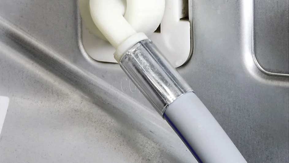 Tuyau blanc fixé avec une attache métallique sur une surface grise, montrant une connexion sécurisée.