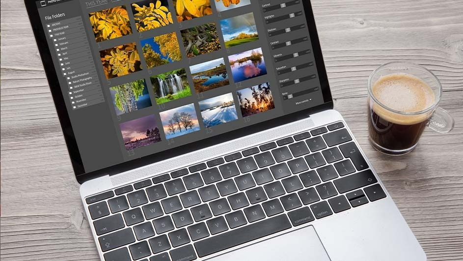 Laptop on a wood table showing photo editing software with nature images and a glass coffee cup.
