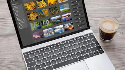 Laptop on a wood table showing photo editing software with nature images and a glass coffee cup.