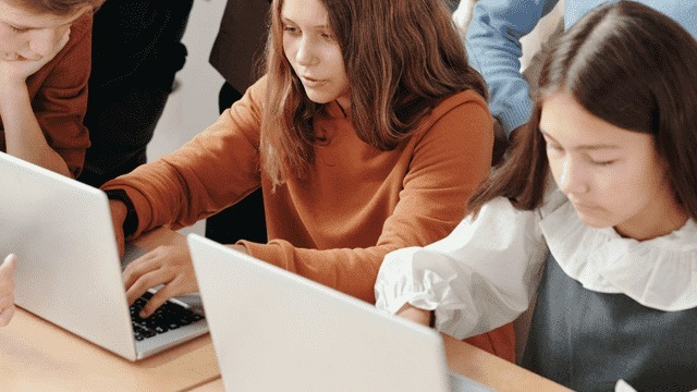 Een groep mensen zit aan tafels met laptops. Ze zijn geconcentreerd aan het typen.