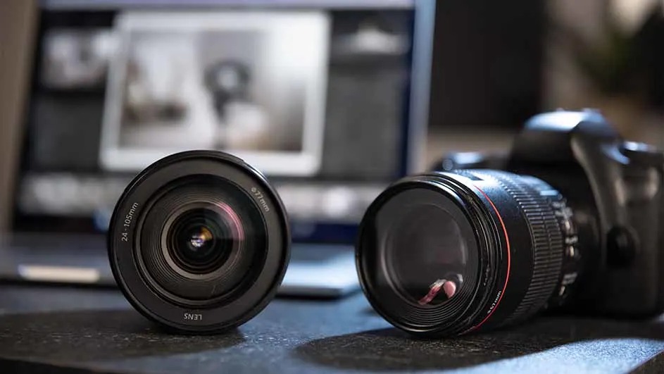 Deux objectifs noirs et un appareil photo numérique sont placés devant un ordinateur portable.