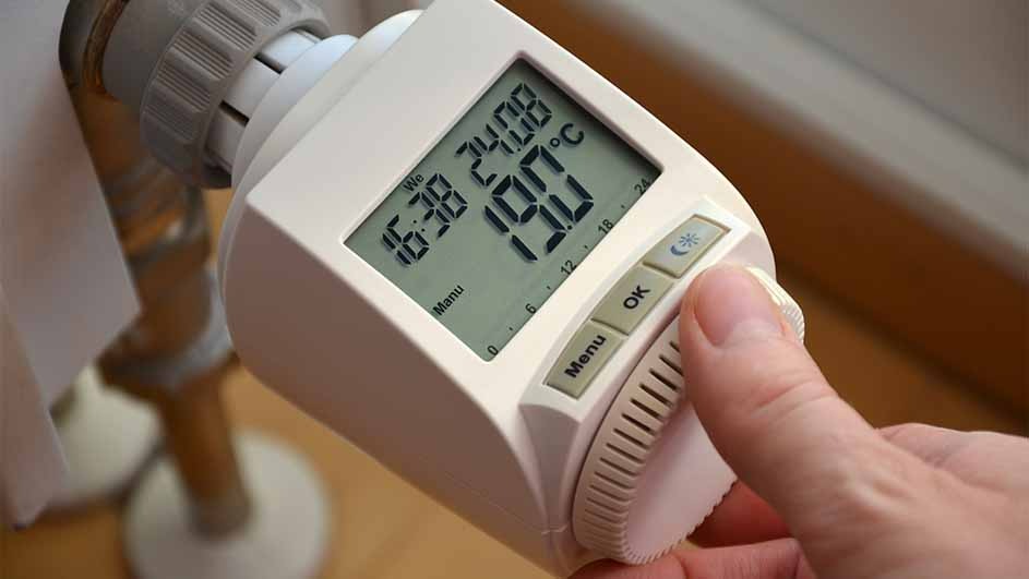 Un radiateur blanc avec affichage numérique montre 19.0°C. Une main ajuste le bouton de réglage.